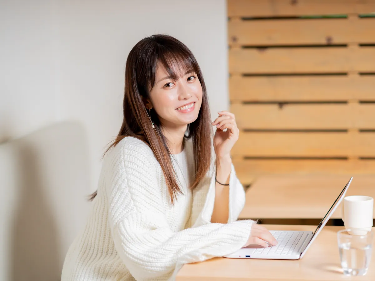 ノートパソコンの前で笑顔で話す女性